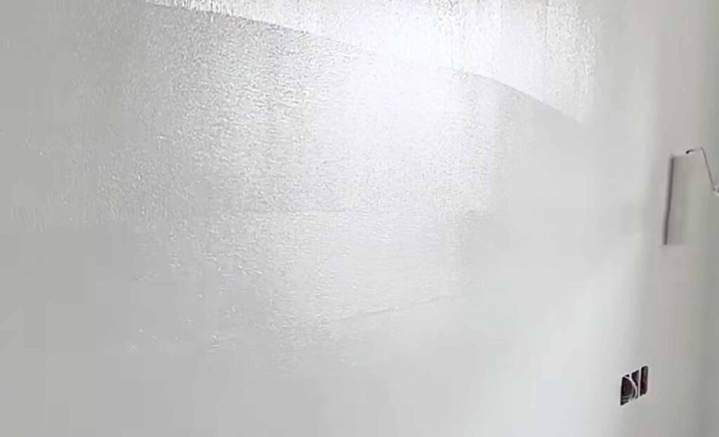 Roller applying potassium silicate coating to concrete wall for waterproofing and efflorescence control