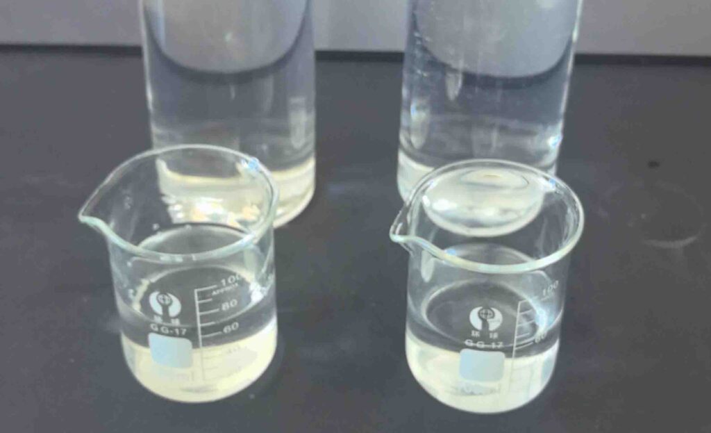 Clear viscous sodium silicate liquid glass in glass beaker showing colorless to slightly blue green transparent appearance