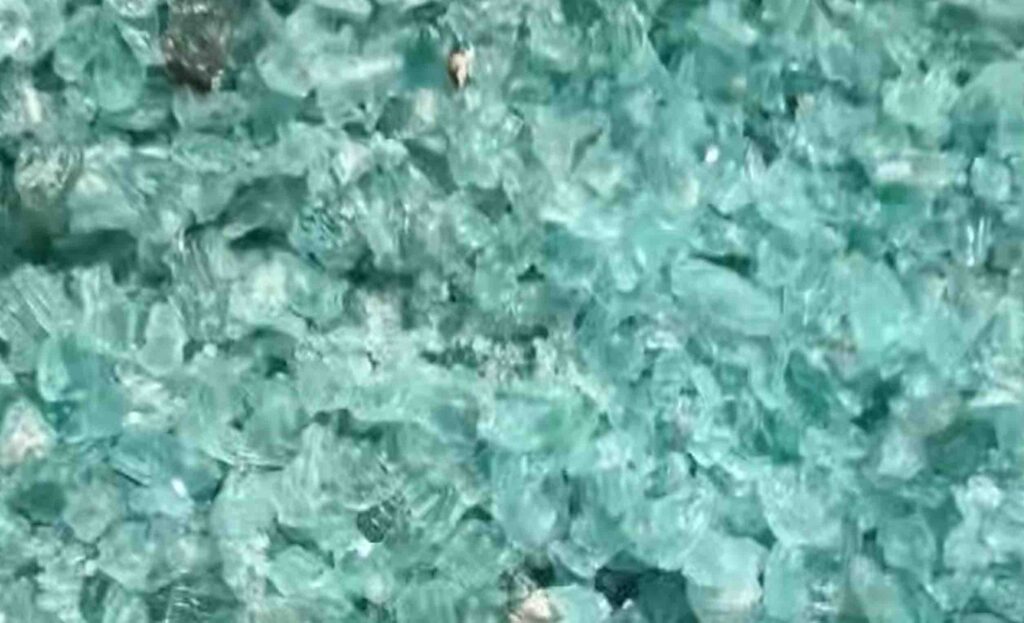 Solid sodium silicate cullet in blue-green glassy lumps and flakes on industrial pallet for storage and transport