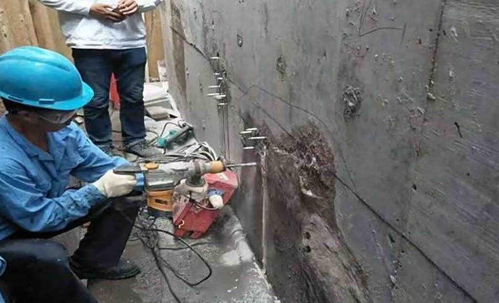Sodium silicate waterproofing being applied to concrete wall with roller forming penetrating sealer that blocks water ingress