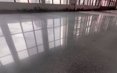 Silicate concrete densifier application on warehouse floor showing hardened dustproof surface with water beading effect